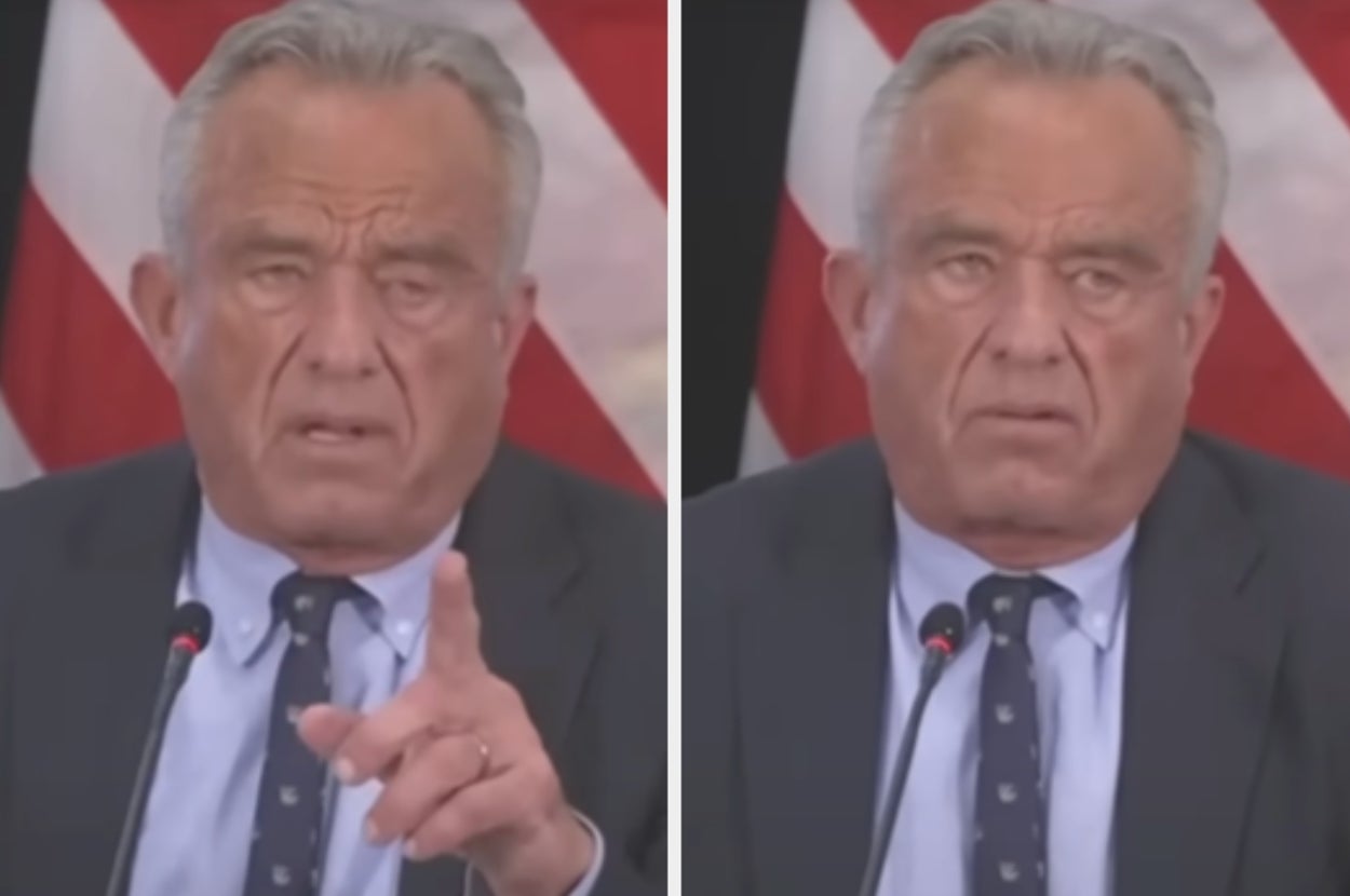 Person in a suit gestures while speaking at a podium, appearing serious and focused