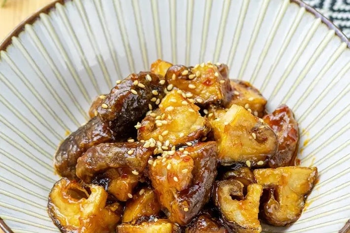 器に盛られた照り焼き風のしいたけとポテトの料理。ゴマが上に振りかけられ、美味しそうにテーブルに置かれている。