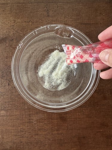 スープ粉末を器に注いでいる様子。透明な器がテーブルに置かれている。