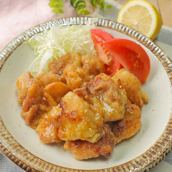 お皿に盛られた唐揚げ、キャベツの千切り、トマトのスライス、レモンが添えられている。