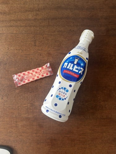 テーブルの上にカルピスのペットボトルと赤い模様の包装紙に包まれたお菓子が置かれている。