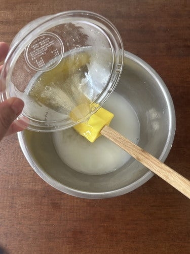 液体と卵白をボウルに注ぎながら混ぜている様子。
