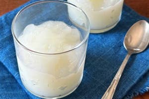 2つのコップに入った氷と飲み物、青い布の上に置かれ、横にスプーンがある。