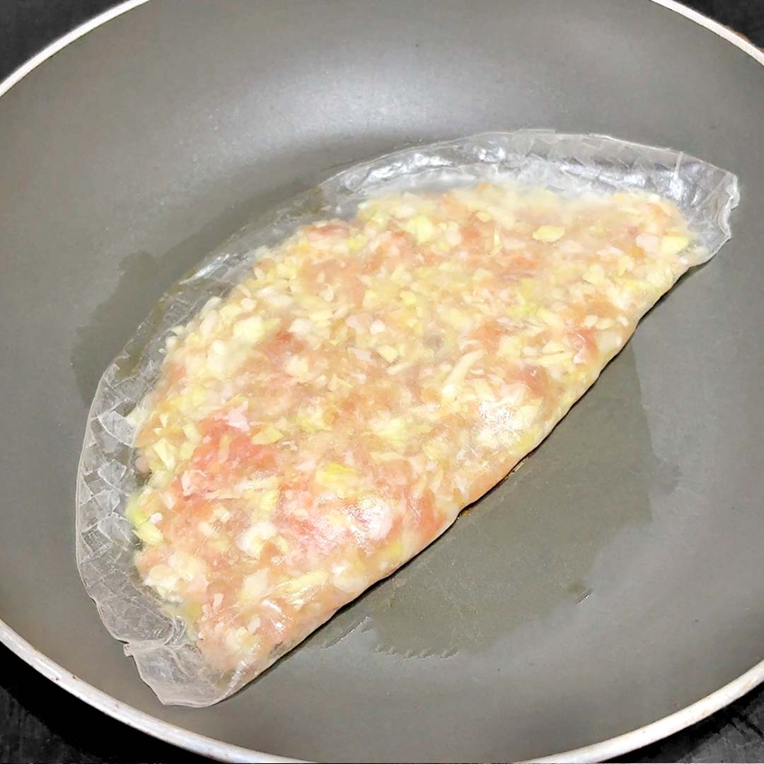 フライパンで加熱中のライスペーパーに包まれた具材。
