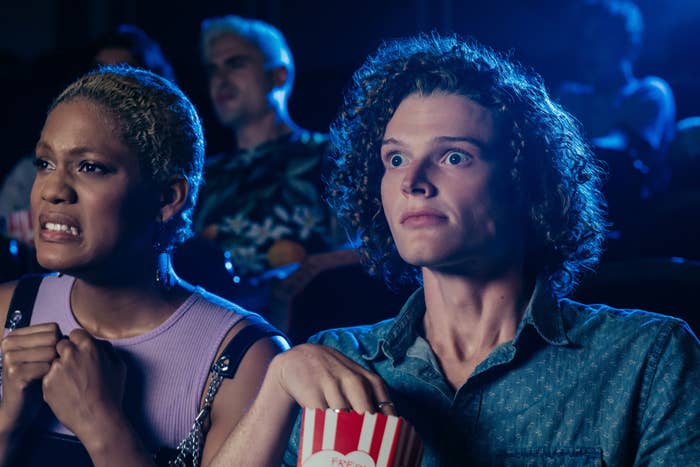 Two radical successful a theatre look amazed and anxious, holding popcorn
