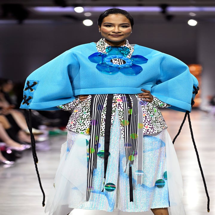 Model on runway in bold geometric-patterned outfit with oversized sleeves and layered skirt