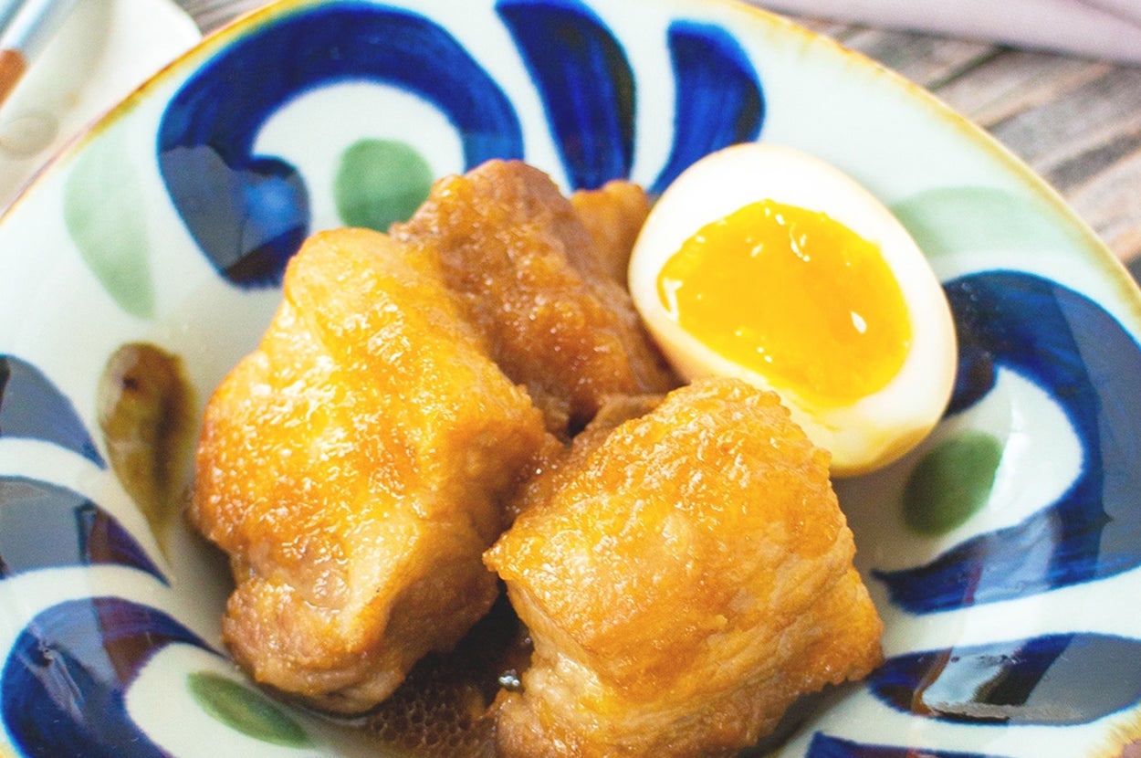 煮卵と豚の角煮が盛られた和風の陶器皿。美味しそうに盛りつけられた一品。