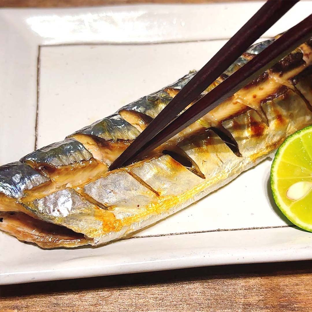 焼き魚が皿に盛られ、箸で切れ込みを見せています。