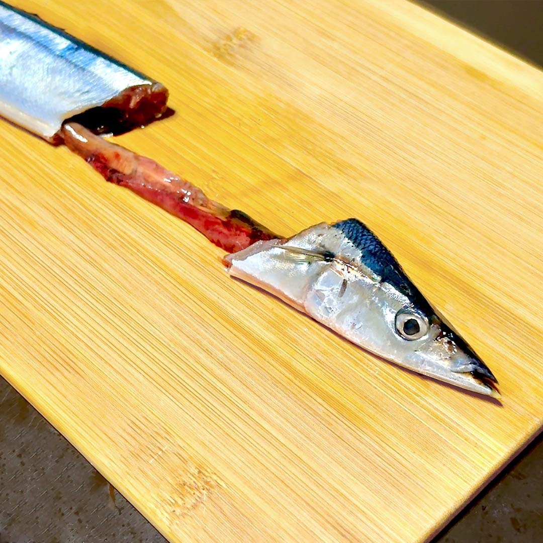 調理中の魚の頭と骨がまな板に置かれている。