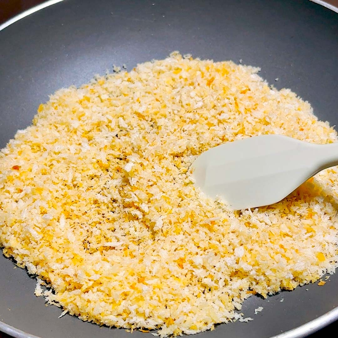パン粉をフライパンで炒めている様子。スパチュラで混ぜている。
