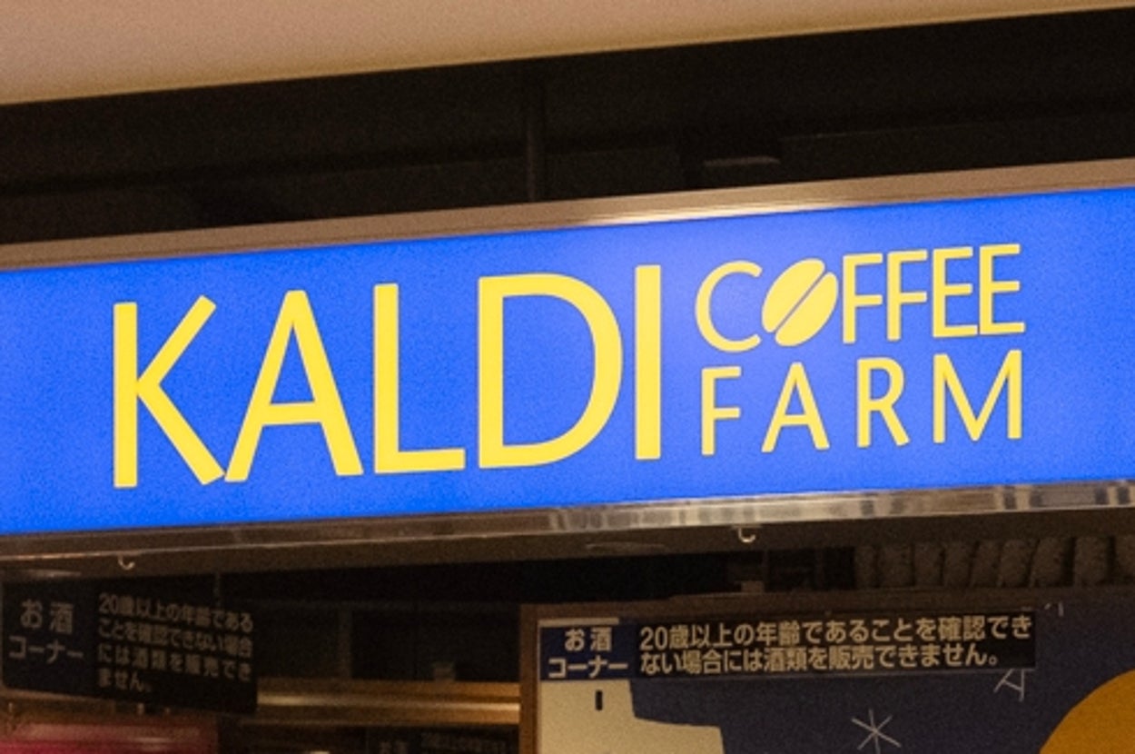 店内の風景。KALDIの看板があり、さまざまな食品や飲み物が棚に並んでいる。買物カートが入口に置かれている。