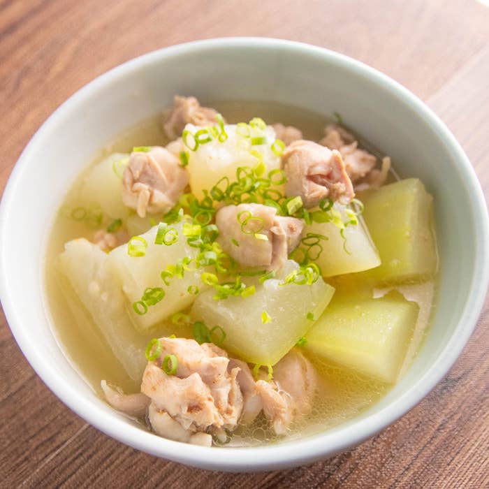 冬瓜と鶏肉のあっさり煮。冬瓜と鶏肉の煮物が入った白いボウル。細かく刻んだネギがトッピングされている。