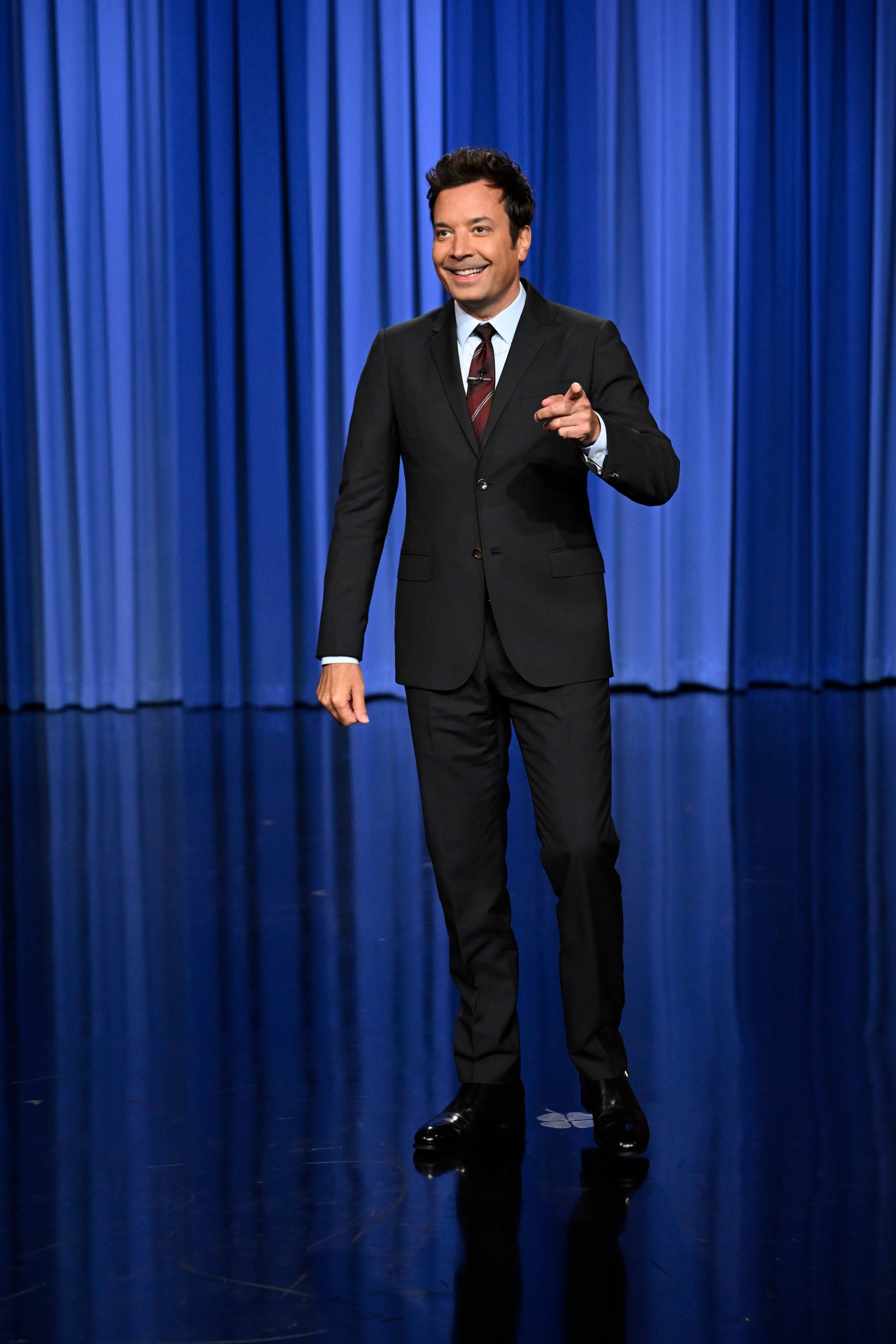 Jimmy Fallon on a stage with a curtain backdrop
