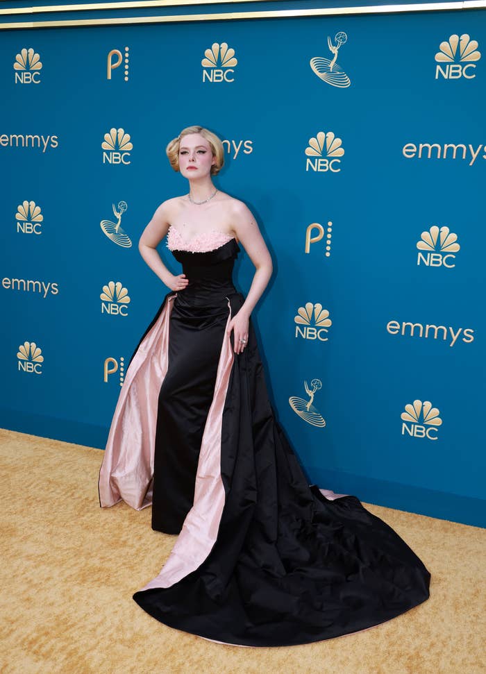 Elle Fanning connected reddish carpet successful elegant achromatic gown with a agelong bid and elaborate neckline, posing confidently
