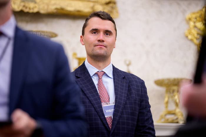 A antheral successful a suit and necktie stands successful an ornate country with golden decor, wearing a visitant badge