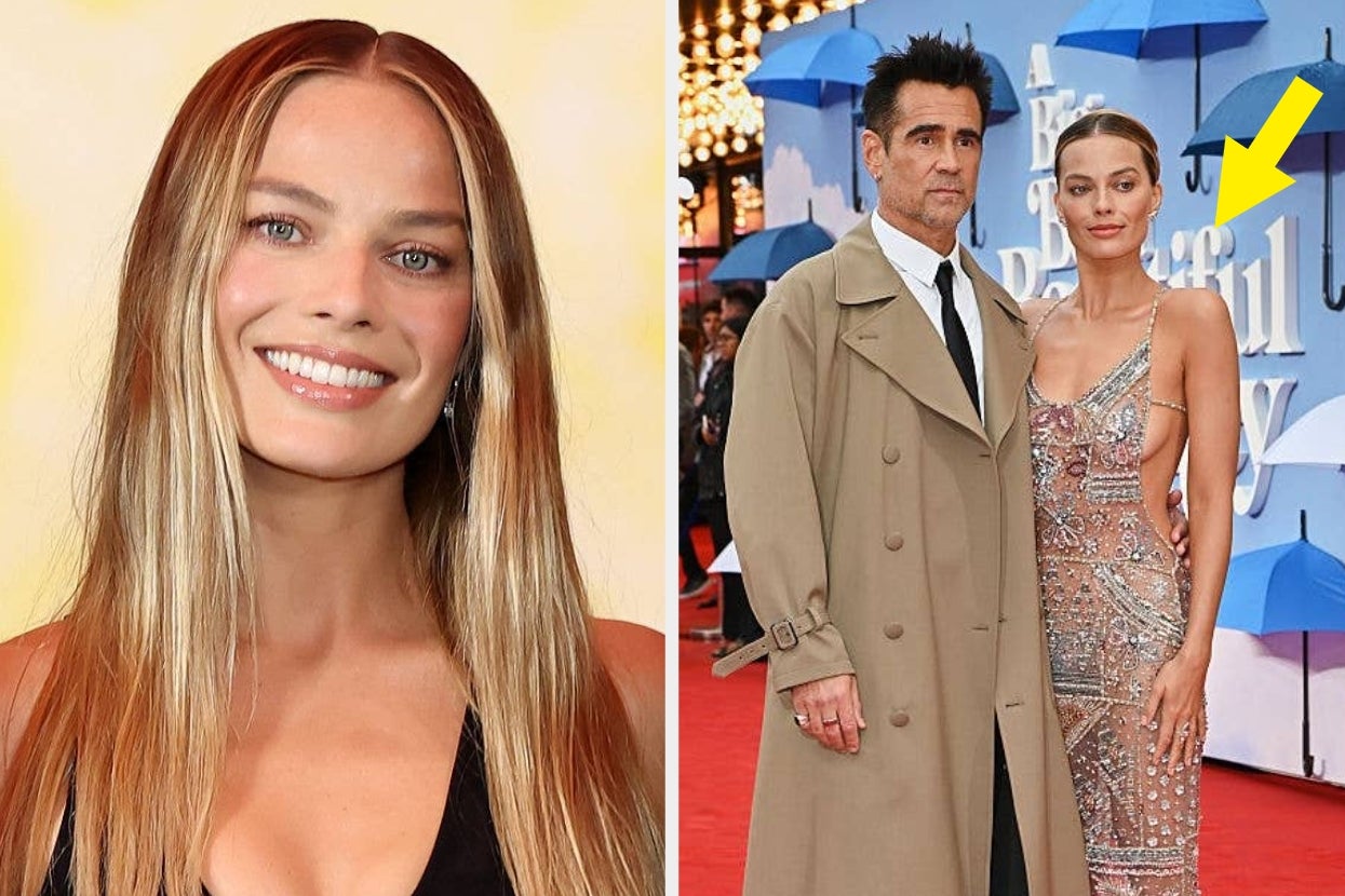 Person in sleek gown poses with another in a classic suit and long coat on the red carpet