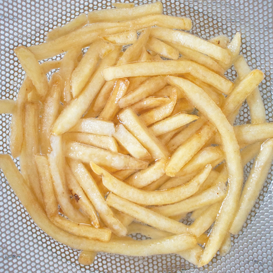 たくさんのフライドポテトが網の上に広がっています。