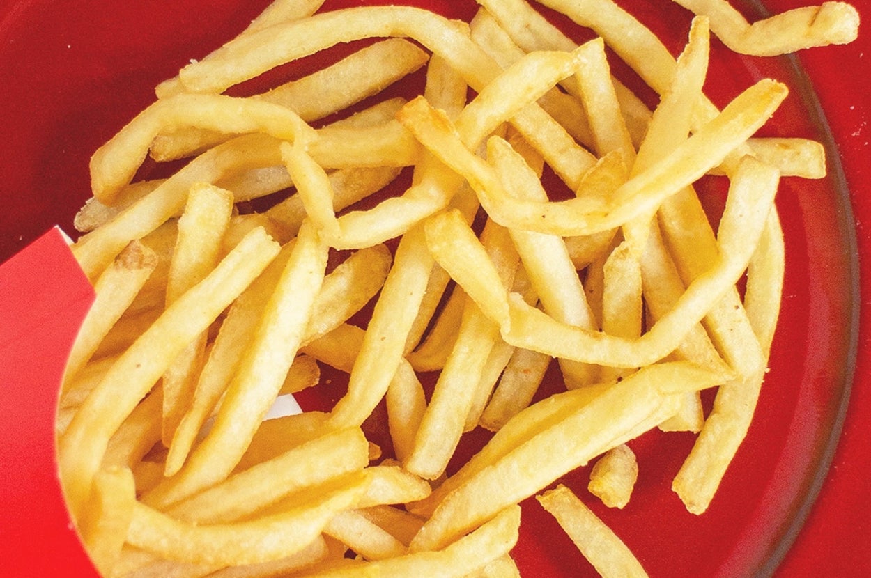 赤い皿の上にフライドポテトが載っている。ポテトはカリカリで食欲をそそる。