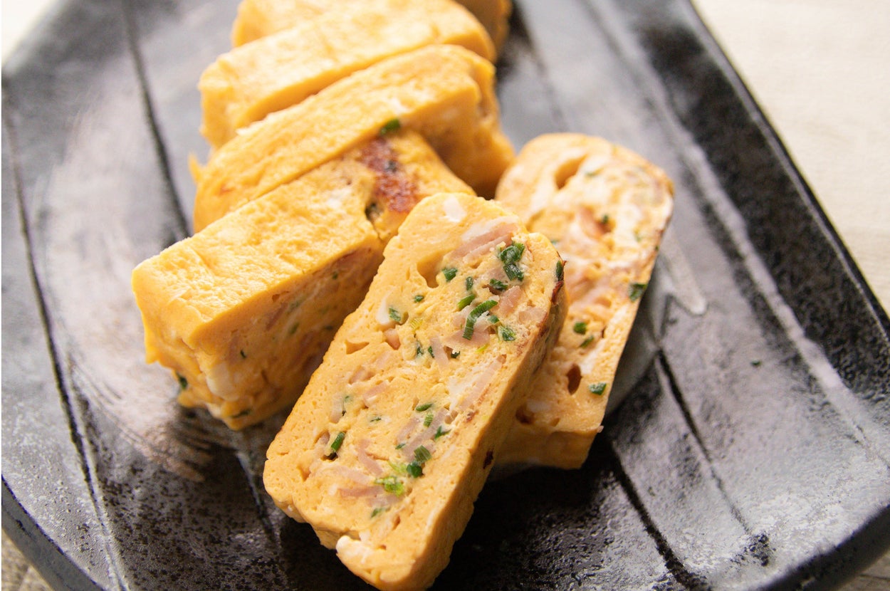 皿に盛られた厚焼きたまご料理。ネギと具材が見える。