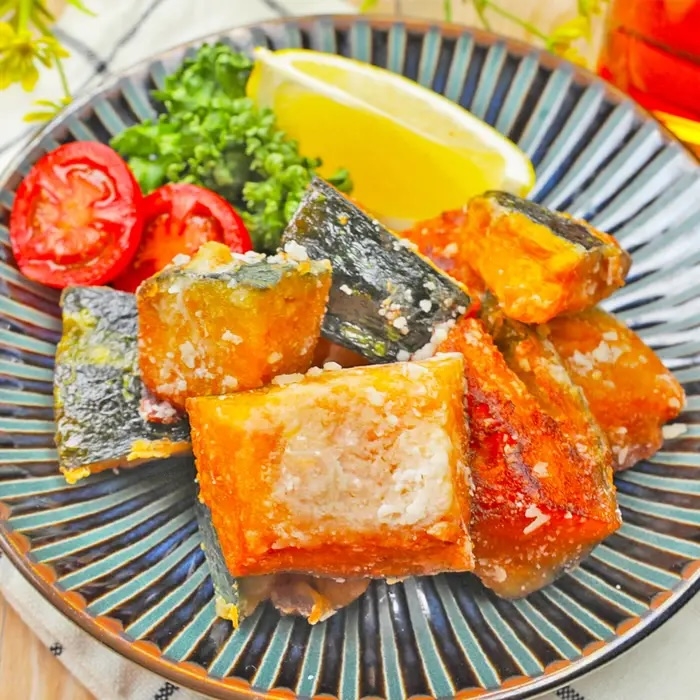 皿に盛られた焼きカボチャと隣のレモン、トマト、パセリ。