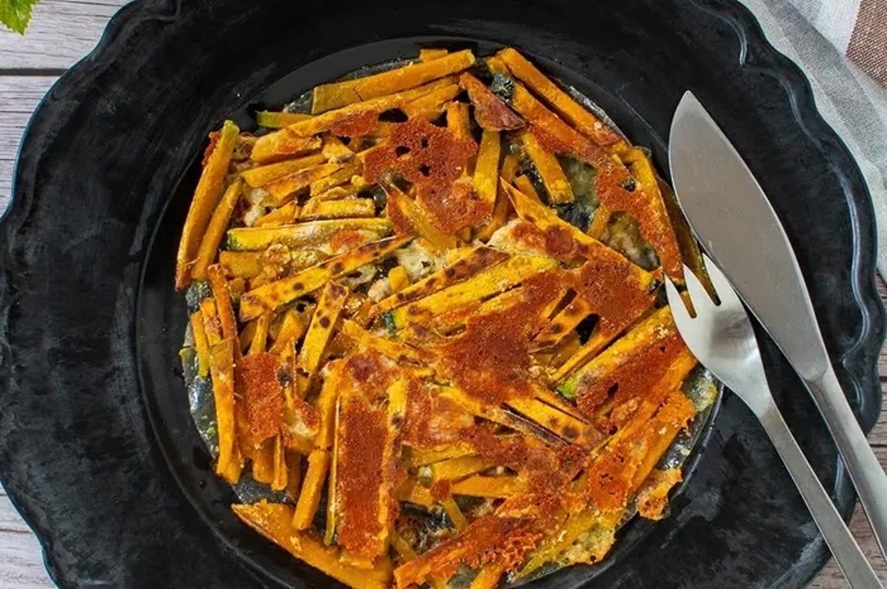 黒い皿に盛られた野菜のオーブン焼き。クリスピーに焼かれた部分が見える。