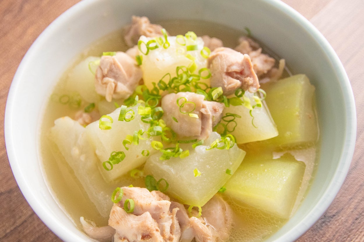 鶏肉と冬瓜が入ったスープの白いボウル。刻んだネギが上に散らされています。