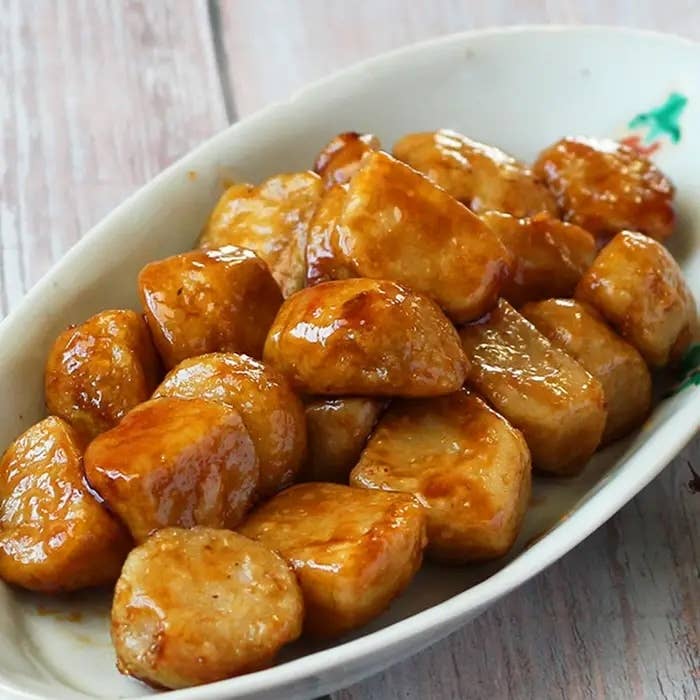 白い皿に盛られた照り焼きソースでコーティングされたチキンナゲット。食欲をそそる光沢がある。