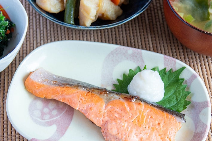 和定食の一例。焼き魚、味噌汁、煮物、小鉢が竹製のマットに並べられている。