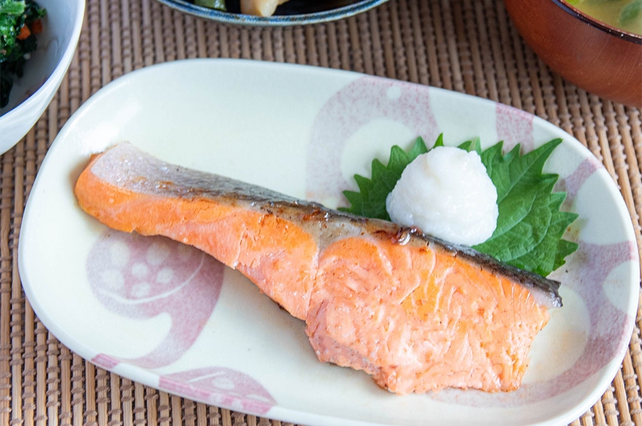 和定食の一例。焼き魚、味噌汁、煮物、小鉢が竹製のマットに並べられている。