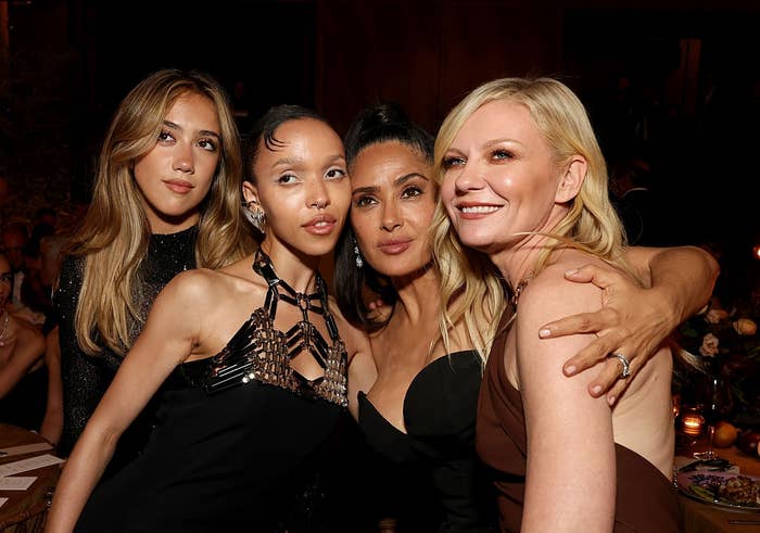 Four women airs unneurotic astatine an indoor event, dressed successful elegant evening gowns. They grin warmly for the camera