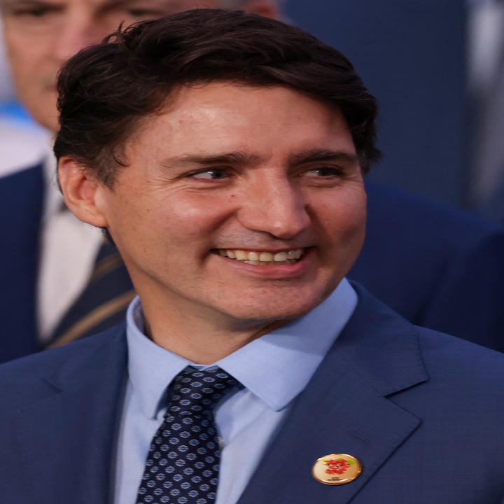 Smiling man in a suit with a pin on his lapel, standing among others at an event