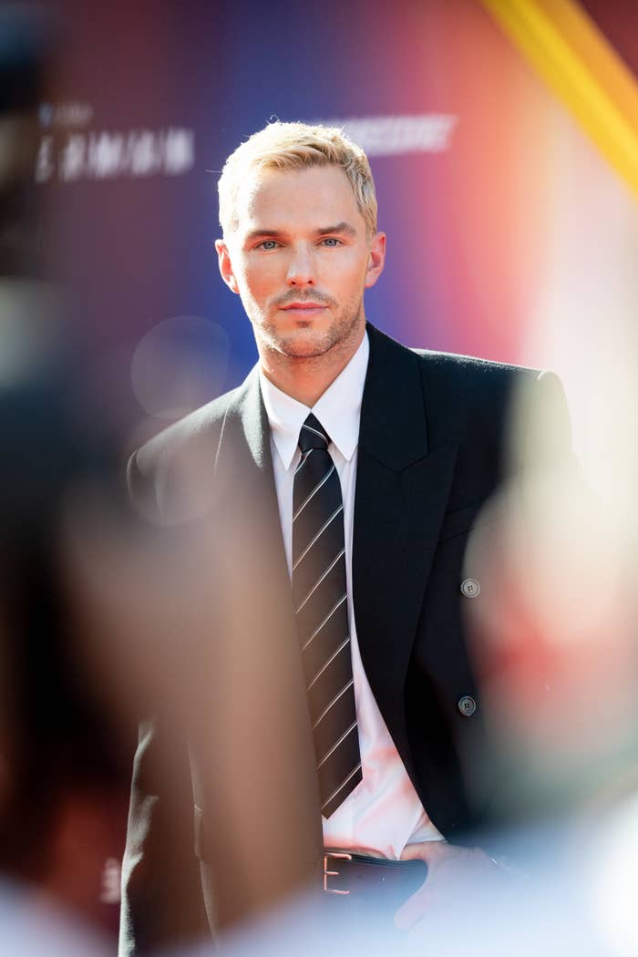 Nicholas Hoult connected the reddish carpet wearing a achromatic suit jacket, achromatic shirt, and striped tie, with abbreviated hairsbreadth styled neatly