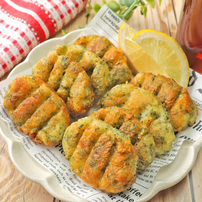 レモンが添えられた揚げたポテト料理が皿に乗っている。新聞の一部が敷かれている。