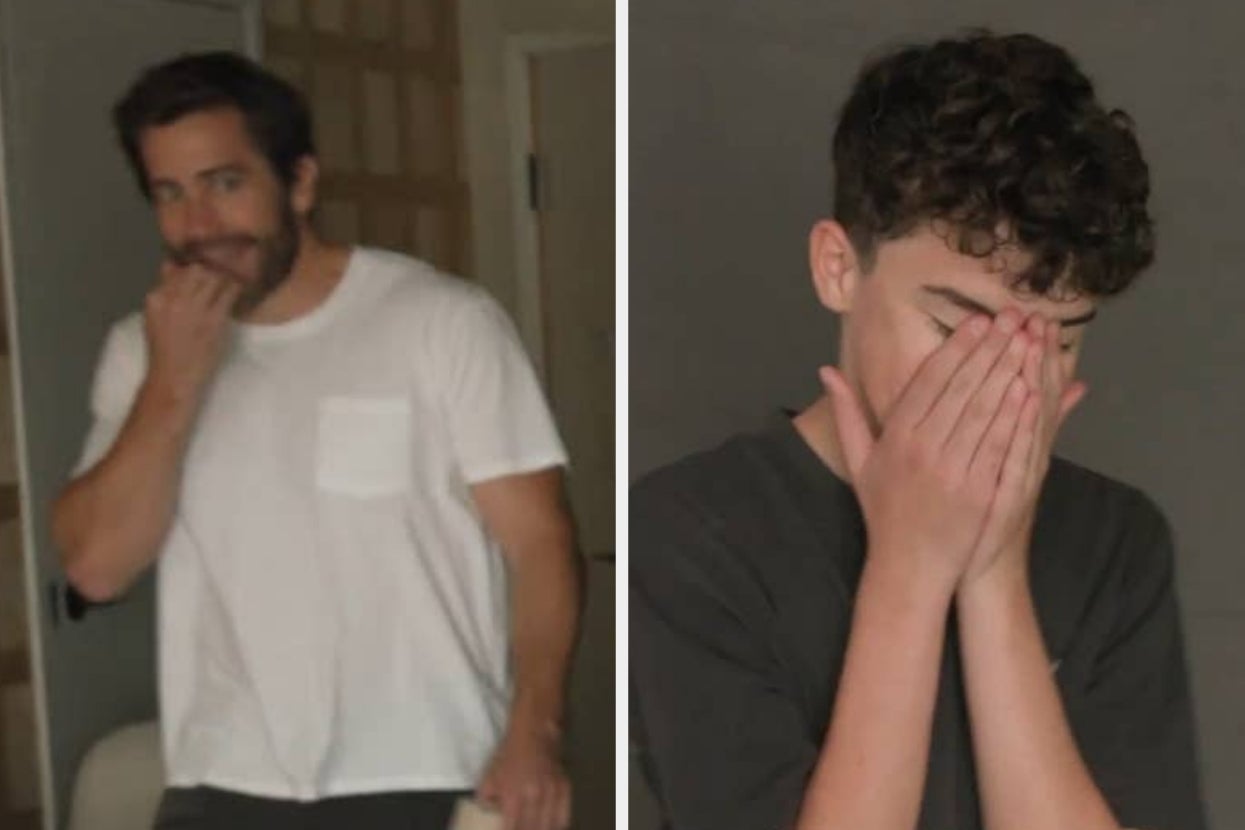 Two individuals, one in a white t-shirt and the other in a dark shirt, both cover their faces with their hands while appearing to laugh