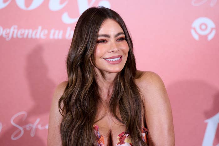 A pistillate with agelong hairsbreadth smiles astatine an event, wearing a colorful floral-patterned dress