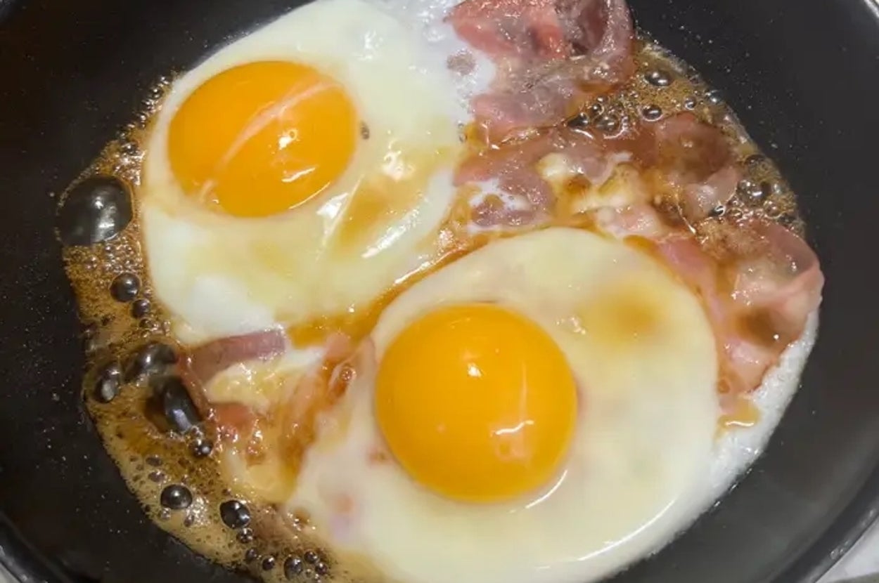 フライパンでベーコンと卵を焼いている様子。ベーコンは香ばしく焼かれ、卵は半熟状態。
