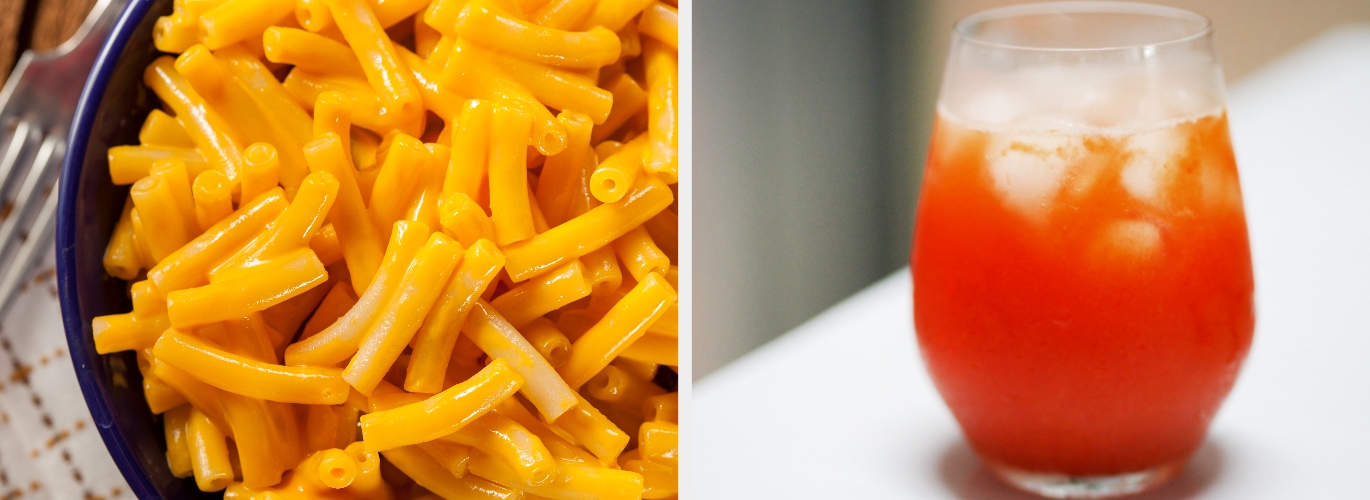 A bowl of macaroni and cheese next to a glass of red-orange iced beverage on a table