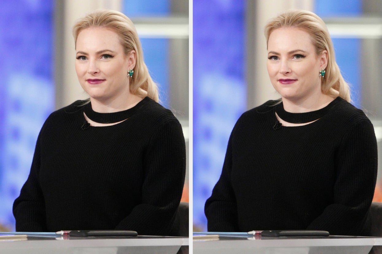 Person in a black sweater with long sleeves, seated at a desk, appearing on a talk show set