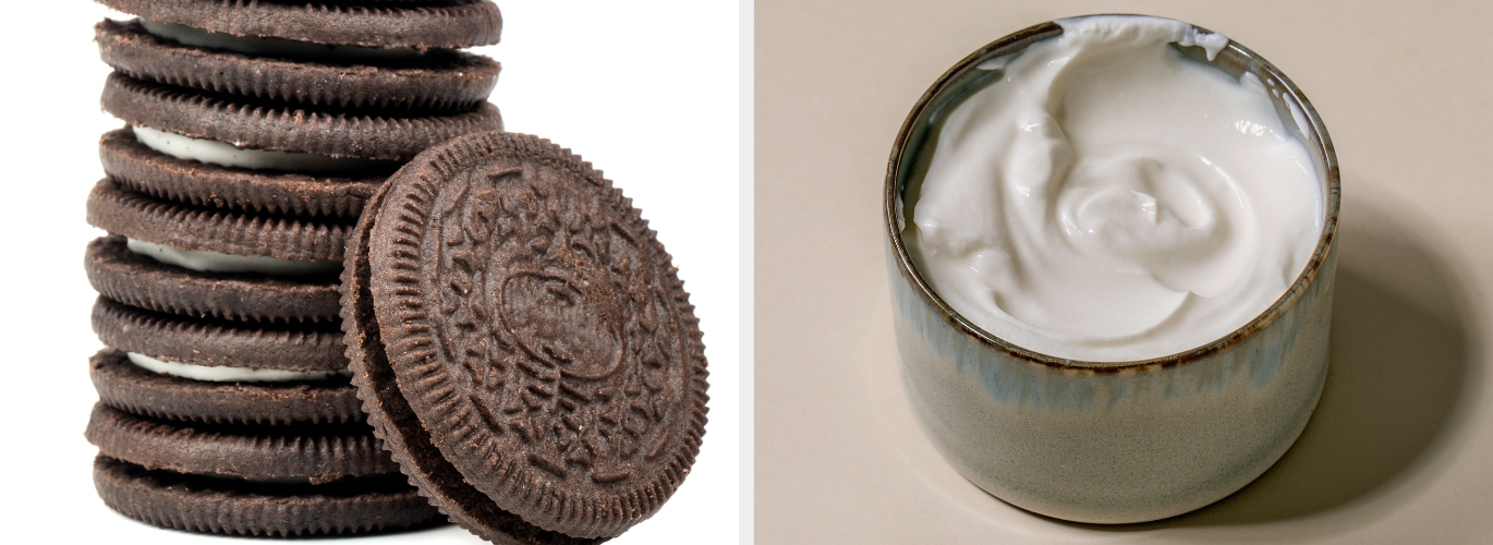 A stack of sandwich cookies next to a bowl of creamy white frosting on a neutral surface