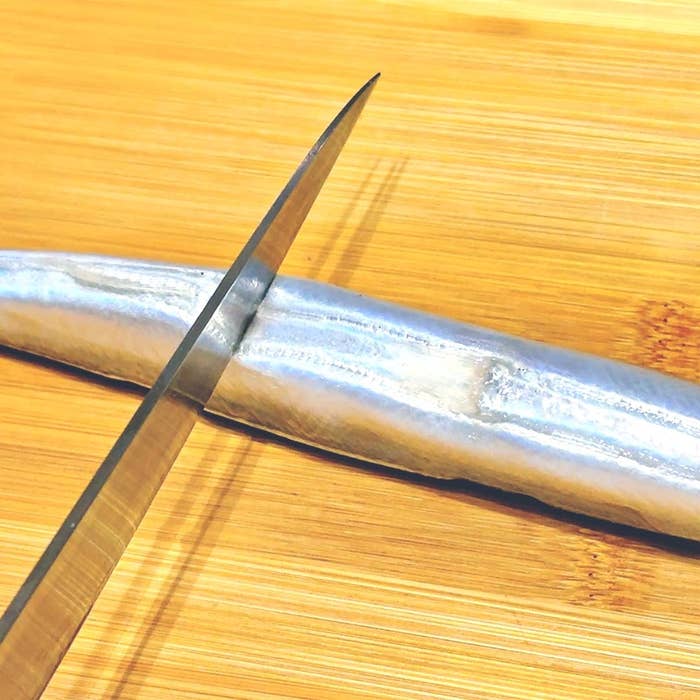 まな板の上で魚を包丁で切る様子。