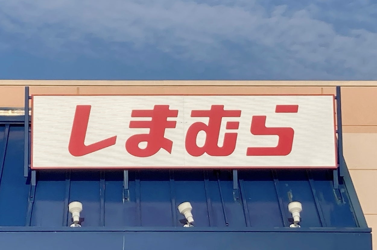 Sign with Japanese text "しまむら" on a store facade under a clear sky