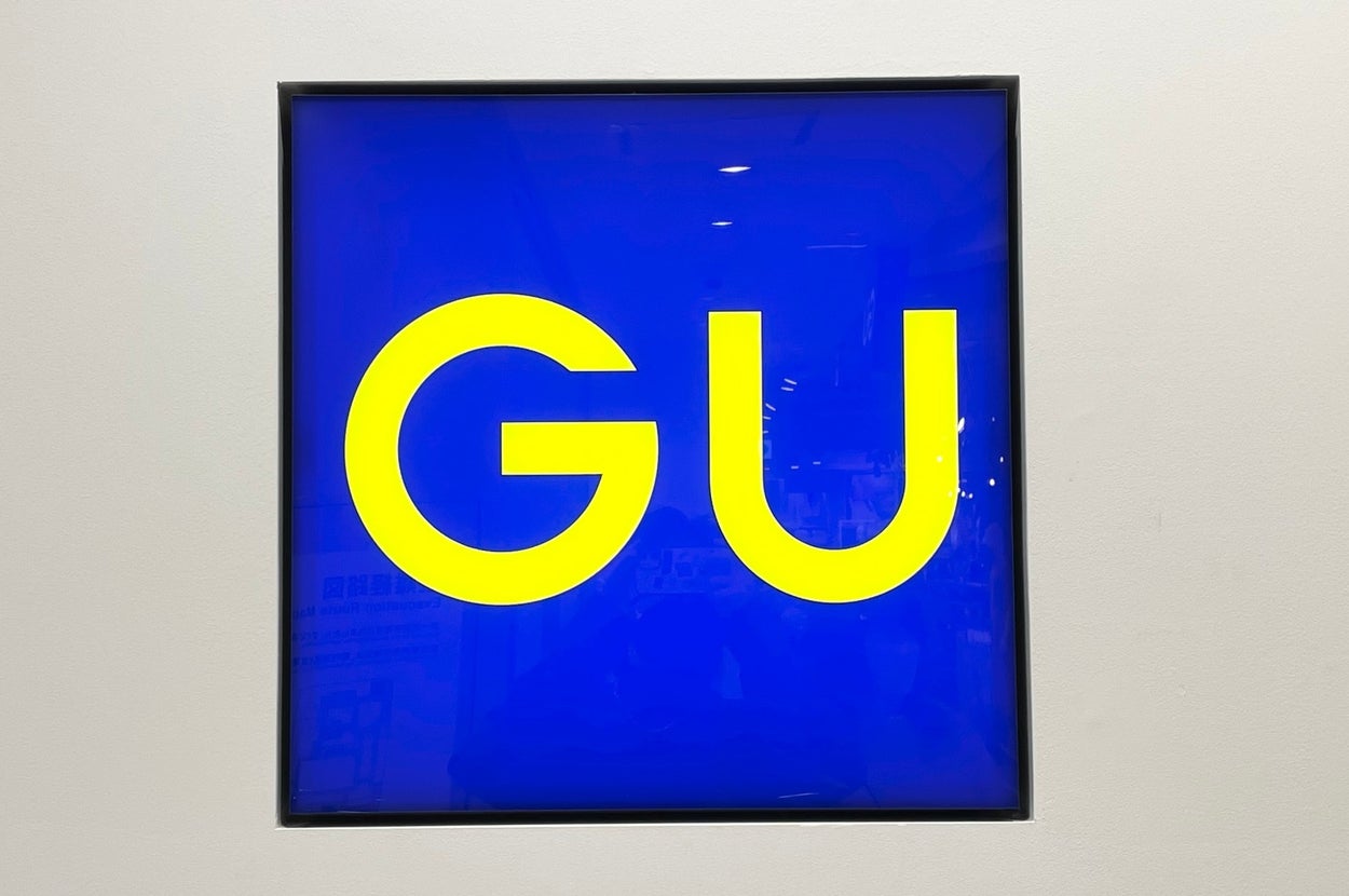 GU store sign with bold, sans-serif yellow letters in a blue square