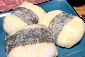 皿に盛られた3つのもちもちしたおにぎり、海苔で巻かれた状態でソースが添えられています。