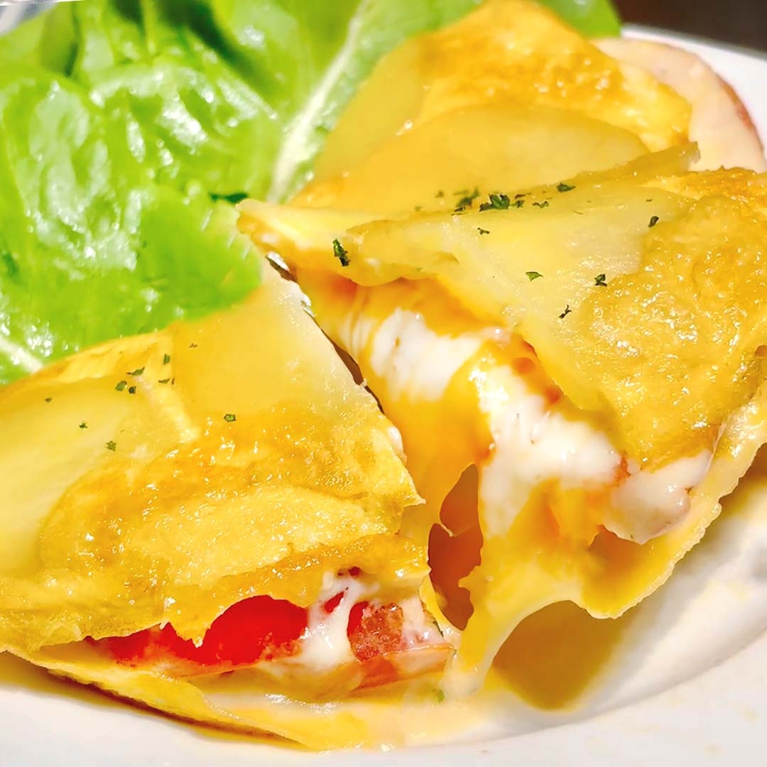 チーズとトマトを挟んだオムレツが切り分けられ、レタスが添えられている。温かくとろけるチーズが特徴的。
