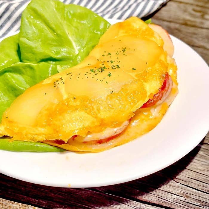 チーズと野菜が入ったオムレツがレタスの上に置かれた白い皿の上にあります。