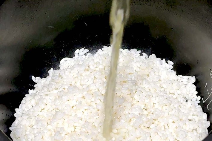 米を炊飯器に入れ、水を注いでいる様子。