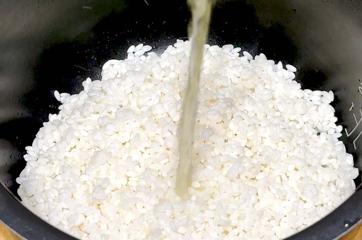 米を炊飯器に入れ、水を注いでいる様子。