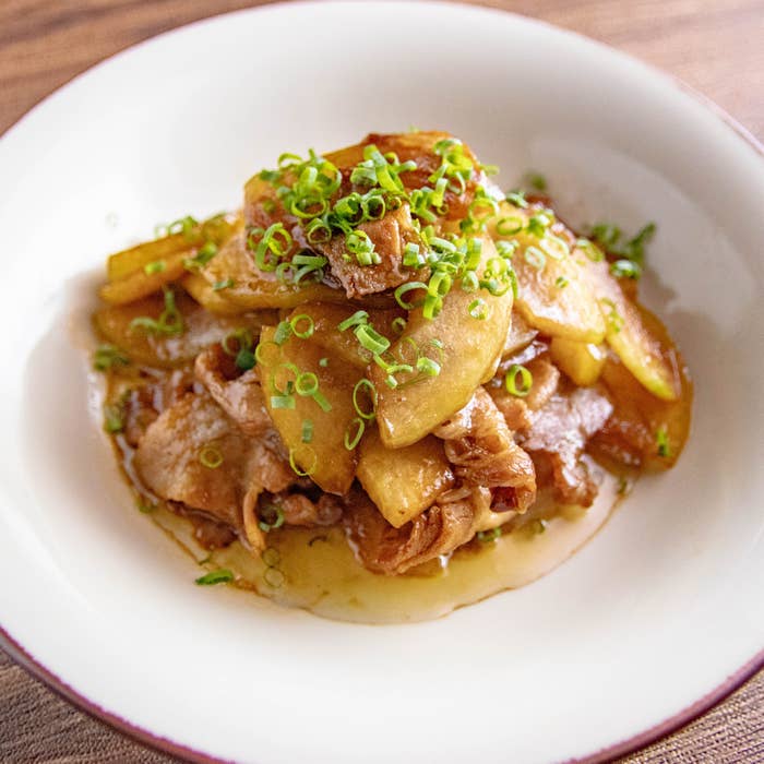 冬瓜と豚バラ肉のオイスターソース炒め。薄切り肉と冬瓜の炒め物が白い皿に盛られている。刻みネギが上に散らされている。