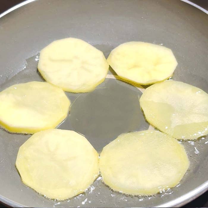 フライパンで焼かれている薄切りポテトの写真。