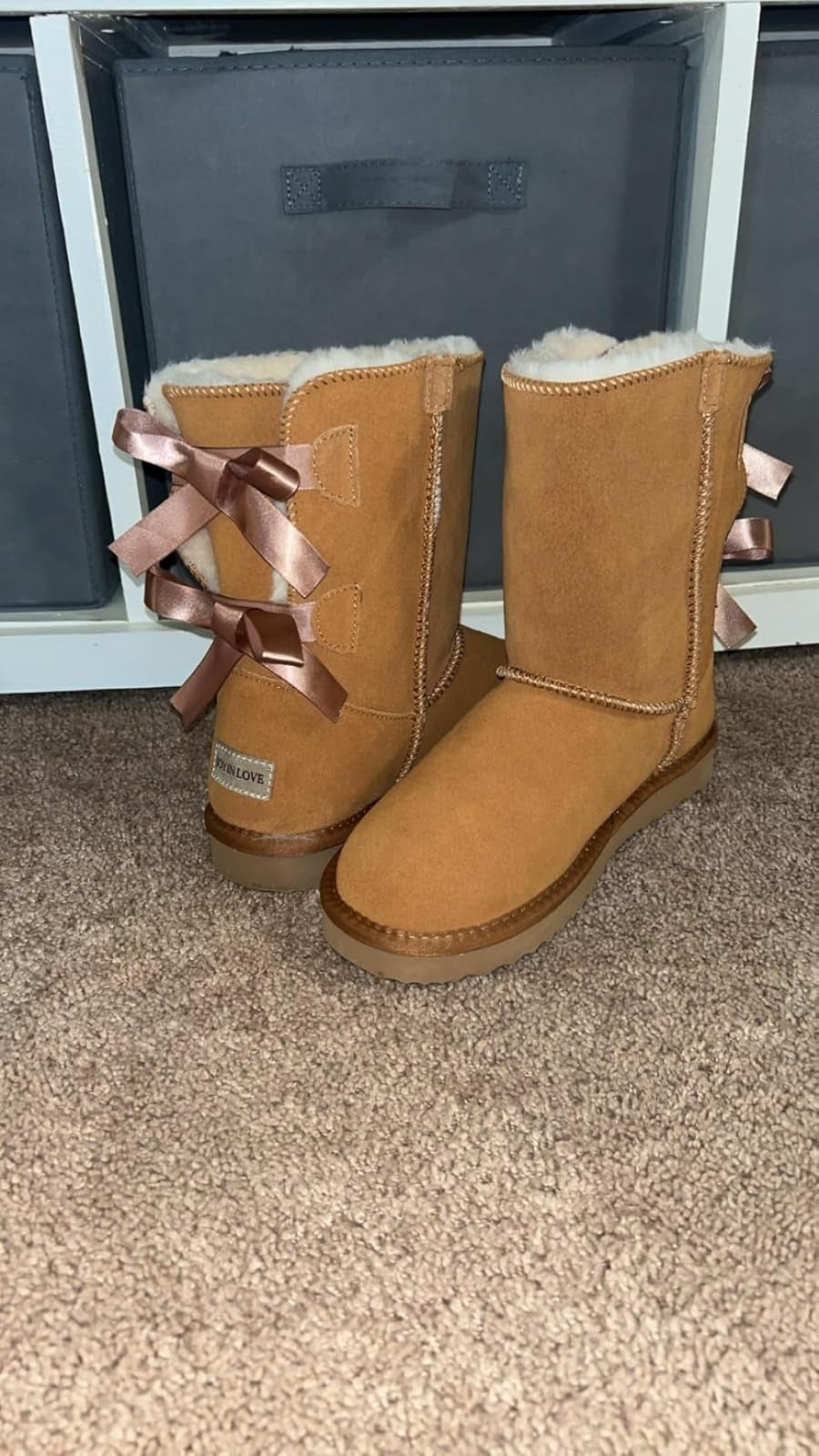boots with faux fur lining and bow accents connected  the back, displayed connected  a carpet successful  beforehand   of retention  bins